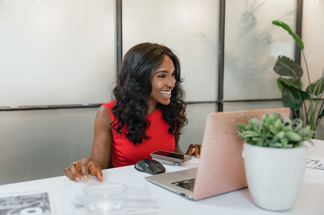 An operator smiling at her desk with a laptop